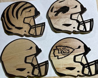 Könnte beinhalten: Vier Untersetzer aus Holz mit einem Footballhelm-Design. Jeder Untersetzer hat ein anderes Teamlogo: einen Tigerstreifen, einen Vogel, ein Kansas City Chiefs-Logo und einen einfachen Helm.