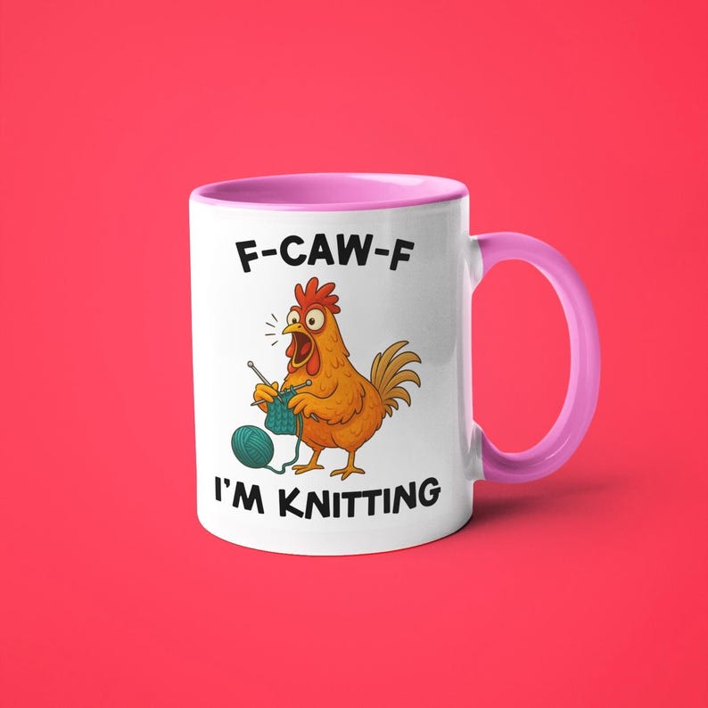 May include: White ceramic mug with a pink interior and handle. The mug features a cartoon chicken knitting with the text "F-CAW-F I'M KNITTING". The chicken is orange and the yarn is teal.
