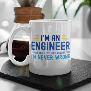 Może przedstawiać: Biały ceramiczny kubek z napisem "I'M AN ENGINEER" w kolorze niebieskim i ż&oacute;łtym. Poniżej znajduje się fraza "TO SAVE TIME LET'S JUST ASSUME THAT I'M NEVER WRONG" w kolorze niebieskim. Kubek ma zakrzywiony uchwyt.