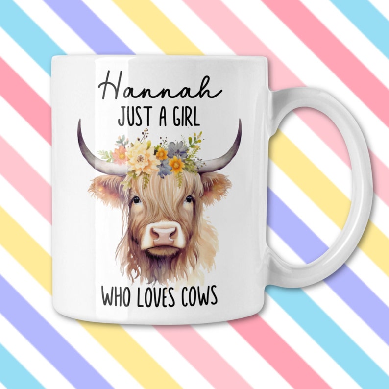May include: White ceramic mug featuring a watercolor illustration of a Highland cow with floral accents and the text "Hannah JUST A GIRL WHO LOVES COWS". The mug has a curved handle and is suitable for hot or cold beverages.