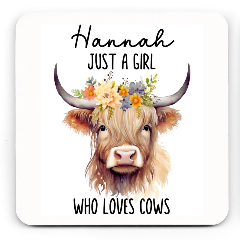 May include: Square coaster featuring a watercolor illustration of a Highland cow with a floral crown. The text reads "Hannah JUST A GIRL WHO LOVES COWS" in black script and block letters. The cow has long, shaggy, light brown fur and large horns.