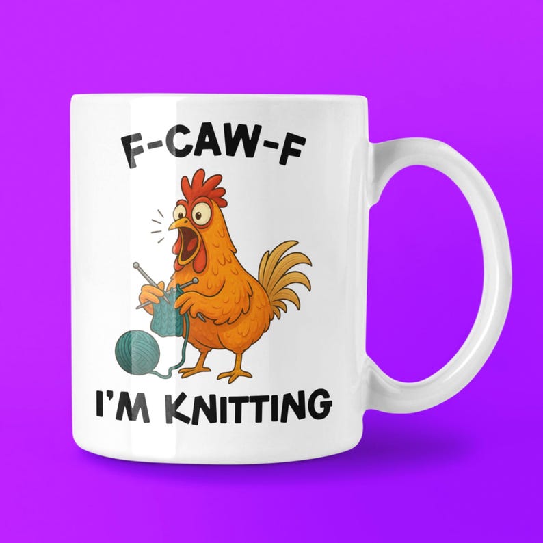 May include: White ceramic mug with a cartoon chicken knitting. The chicken is orange with a red comb and is holding knitting needles and blue yarn. Text on the mug reads "F-CAW-F I'M KNITTING".