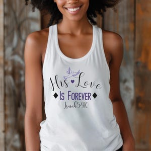 Könnte beinhalten: Weißes Tanktop mit dem Text "His Love Is Forever" und "Isaiah 54:10" in lila Schrift. Ein kleines lila Herz und ein Paar lila Tauben befinden sich über dem Text.