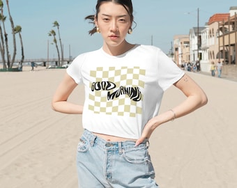 May include: White cropped t-shirt with a checkered pattern in beige and white. The words "GOOD MORNING" are written in a black, stylized font across the checkered pattern.