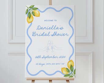 May include: A blue and white welcome sign with a lemon theme for a bridal shower. The sign says "Welcome to Daniella's Bridal Shower" and includes the date "26th September 2024" and the countdown "23 days until the big day!"