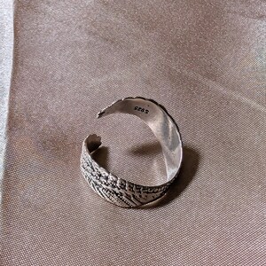 May include: A silver-colored adjustable ring with an open design. The ring features an intricate leaf pattern on the band and is stamped with "S925". The ring is set against a neutral background.