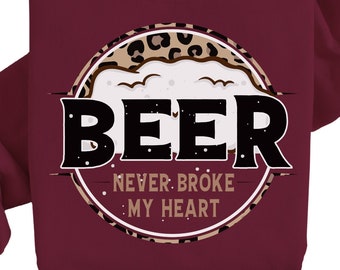 May include: Burgundy sweatshirt with a circular graphic that says "BEER NEVER BROKE MY HEART." The graphic features a leopard print border and a beer mug design with white foam. The sweatshirt is made of a soft material.