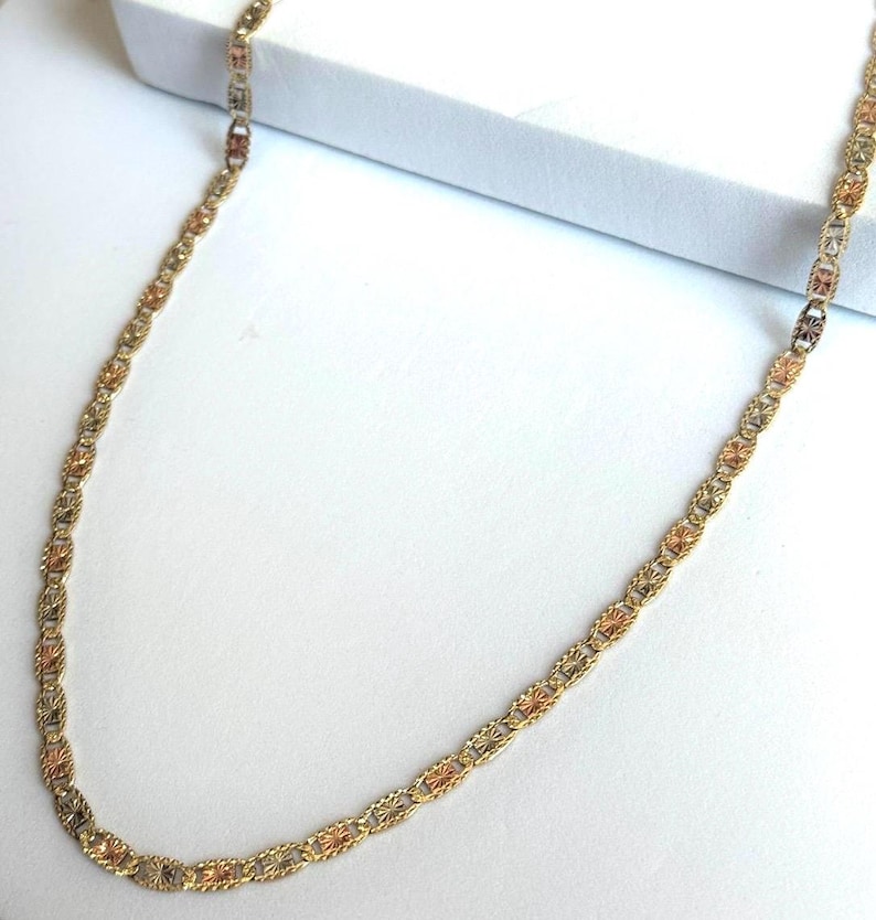 Op de afbeelding: Een goudkleurige ketting met een delicaat kettingontwerp. De ketting heeft afwisselende secties van goud, ros&eacute;goud en zilverkleurig metaal, waardoor een driekleurig effect ontstaat. De ketting wordt gepresenteerd op een witte ondergrond.