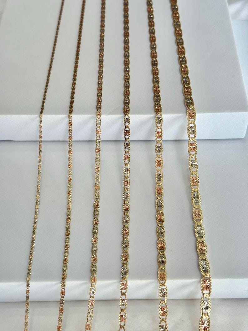 Op de afbeelding: Een assortiment gouden kettingen met verschillende kettingstijlen. De kettingen worden verticaal weergegeven en tonen verschillende ontwerpen en texturen. De kleuren vari&euml;ren van geel tot ros&eacute;goud, met ingewikkelde patronen en schakels.