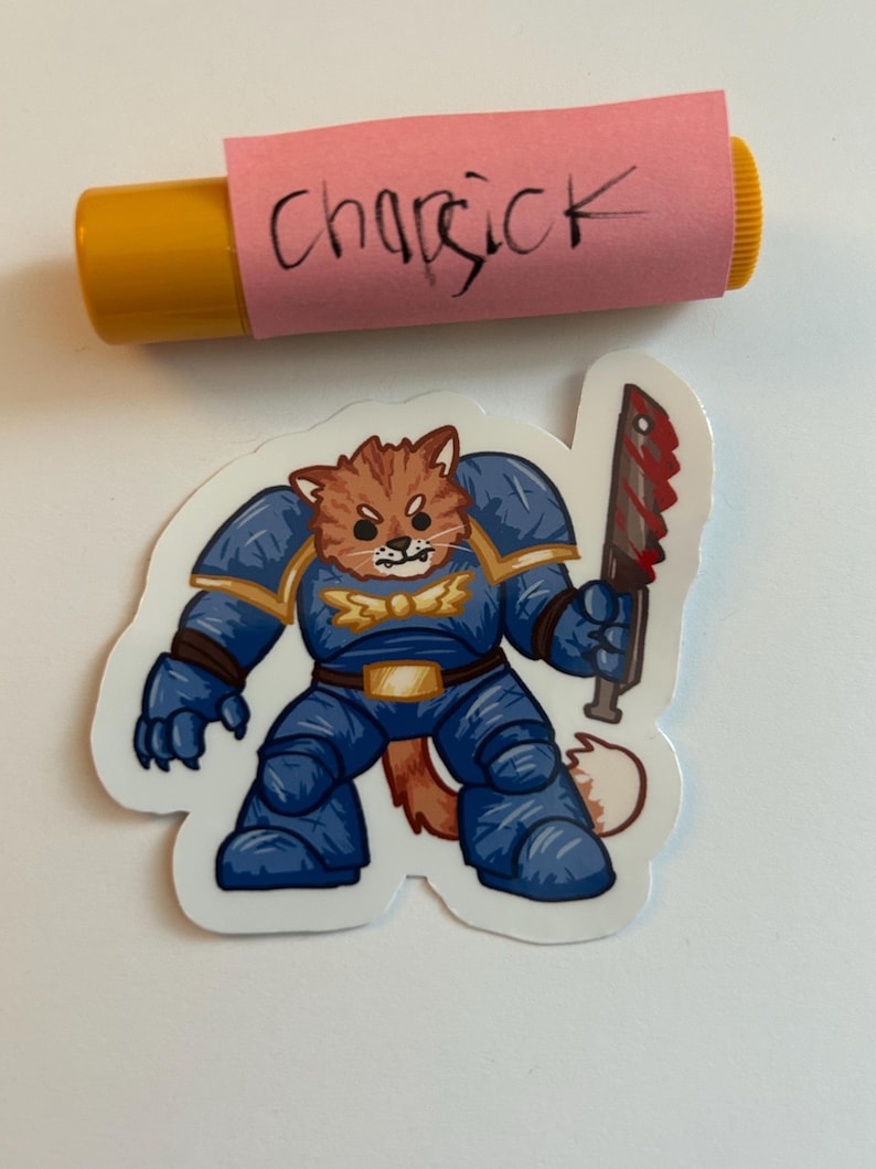Puede incluir: Un gato de dibujos animados azul y naranja con armadura y sosteniendo una espada ensangrentada. El gato tiene una expresi&oacute;n feroz en su rostro. La pegatina est&aacute; sobre un fondo blanco.