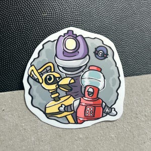 Puede incluir: Una pegatina con un grupo de robots de dibujos animados en amarillo, rojo y morado. Los robots tienen varias formas y diseños, uno de ellos se asemeja a un dispensador de agua. La pegatina tiene un fondo gris y un borde blanco.
