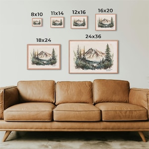 Visual size chart for framed Mount Rainier watercolor mountain art, showing dimensions from 8x10 to 24x36 displayed above a brown leather couch.