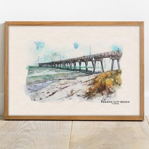 Könnte beinhalten: Ein Aquarellbild einer Seebrücke, die sich über einen Sandstrand und türkisfarbenes Wasser erstreckt. Die Brücke hat ein Holzgeländer und wird von weißen Säulen getragen. Das Bild ist in einem hellbraunen Holzrahmen gerahmt. Der Text "PANAMA CITY BEACH FLORIDA" ist in der rechten unteren Ecke des Bildes gedruckt.