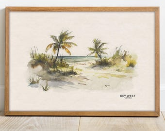 May include: Watercolor painting of a beach scene with two palm trees and a sandy path leading to the ocean. The painting is framed in a light wood frame and has the text "KEY WEST FLORIDA" at the bottom.