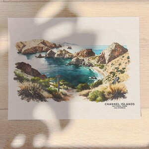 以下が含まれることがあります： カリフォルニア州チャネル諸島国立公園の風景を描いた水彩画。絵画は、ターコイズブルーの入り江と砂浜のある岩だらけの海岸線を表しています。絵画の下部には「CHANNEL ISLANDS NATIONAL PARK CALIFORNIA」というテキストがあります。