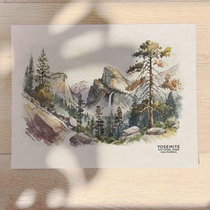 以下が含まれることがあります： カリフォルニア州ヨセミテ国立公園の水彩画。絵画は、崖の側面を流れ落ちる滝のある山脈を描いています。前景には木々があり、背景には青い空があります。