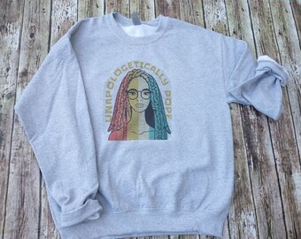 May include: Gray sweatshirt with a vintage-style graphic of a woman with dreadlocks and glasses. The text "Unapologetically Dope" is printed in a circular arc around the woman's head.