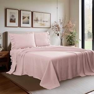May include: A light pink bed set with ruffled pillowcases and a matching bedspread. The bedding is neatly arranged on a bed, creating a soft and inviting look. The set includes two pillowcases and a fitted sheet.