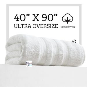 May include: White bath towel rolled up, 40 inches by 90 inches, labeled "Ultra Oversize" and "100% Cotton".