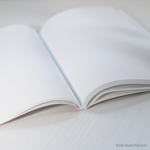 May include: A blank 5x8 sketchbook with white pages, open to a fresh page.