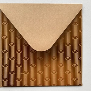 May include: A brown envelope with a gold geometric pattern. The envelope has a flap on the top and is closed.