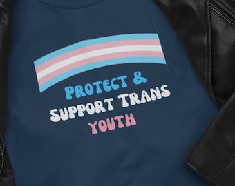May include: A navy blue t-shirt with a transgender pride flag and the text "Protect & Support Trans Youth" in a retro font.