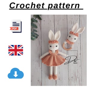 以下が含まれることがあります： ウサギのドールとウサギのガラガラのためのクロシェパターン。ウサギのドールはピーチ色のドレスを着ており、白い毛皮をしています。ガラガラは木でできており、ピーチ色のクロシェのリングが付いています。パターンはPDF形式で入手可能で、英語です。