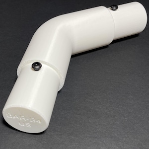 May include: A white, curved roll bar bend with a 125-degree angle, shown against a dark background. The bend has a cylindrical shape with black fasteners and the text "BAR-34 US" printed on one end.