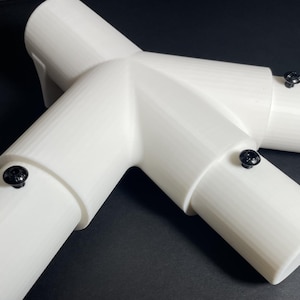 Puede incluir: Conector angular A-Pilar 180-65-45 de plástico blanco con tres aberturas cilíndricas y tornillos negros. El conector está diseñado para unir tubos en ángulos específicos. El texto "A-Pillar 180-65-45 Angle Shown" es visible.