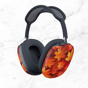 May include: Over-ear headphones with a dark gray headband and earcups. The earcups feature a vibrant pattern of orange, red, and yellow autumn leaves. The headphones are designed for comfort and style.