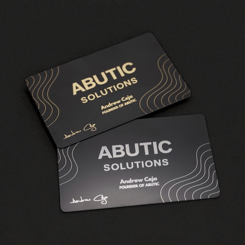 May include: Two black business cards with rounded corners. The cards feature the text "ABUTIC SOLUTIONS" in gold and white, with the name "Andrew Ceja" and the signature of Andrew Ceja. The cards have a wavy design.