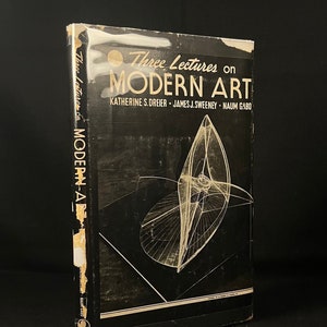 以下が含まれることがあります： キャサリン・S・ドレイアー、ジェームズ・J・スウィーニー、ナウム・ガボによる「モダニズムに関する3つの講義」というタイトルの黒い本。表紙には、幾何学的な彫刻の白黒のイラストが描かれている。