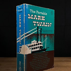 May include: A blue and white book titled "The Portable Mark Twain" with a steamboat illustration on the cover. The book is part of the "The Viking Portable Library" series.