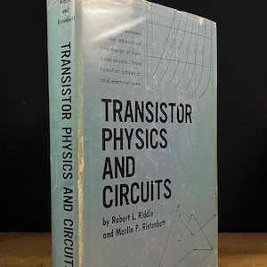 Puede incluir: Un libro antiguo titulado "TRANSISTOR PHYSICS AND CIRCUITS" de Robert L. Riddle y Marlin P. Ristenbatt. El libro tiene una cubierta azul claro con texto y diagramas en negro. El libro está sobre una superficie de madera.