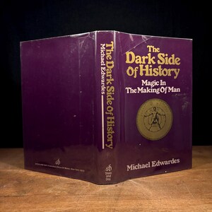 May include: A hardcover book titled "The Dark Side of History" by Michael Edwardes. The cover is a deep purple with gold lettering and a circular illustration. The book's spine also displays the title and author.