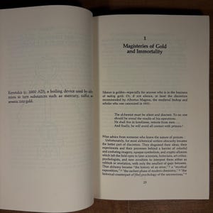 May include: Open book pages with text about alchemy, including the title "Magisteries of Gold and Immortality." The text describes the Kerotakis, a boiling device, and discusses the secrecy of alchemists. The page number 23 is visible.