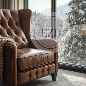 May include: A brown leather armchair with a high back and button detailing. The chair is positioned near a large window offering a view of snow-covered trees and mountains. A beige throw blanket is draped over the arm.