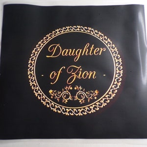 Puede incluir: Un fondo negro con un círculo dorado que contiene el texto "Daughter of Zion" en una fuente decorativa. El círculo está rodeado por un borde dorado adornado.