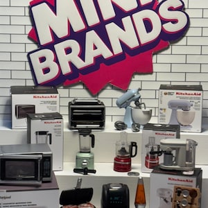 Può includere: Una collezione di elettrodomestici da cucina in miniatura, tra cui un forno tostapane, un frullatore, un robot da cucina, un forno a microonde, una friggitrice ad aria e una planetaria. Gli elettrodomestici sono tutti di colori e stili diversi e sono disposti su una superficie piastrellata bianca. L'immagine include anche una piccola lampada a lava e un mini-ferro da waffle.