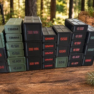 May include: A collection of stacked, rectangular black and green boxes with red and green text. The boxes are labeled with various ammunition types, including "556", "9MM", "40 S&W", "45 ACP", and "308 WIN". The boxes are arranged on a wooden surface.