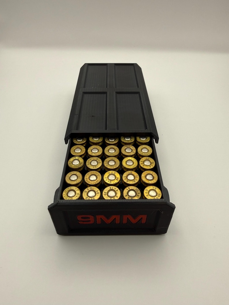 May include: A black 9MM ammunition storage box with a hinged lid, filled with brass-colored bullets. The box has red lettering that reads "9MM". The bullets are neatly arranged inside the box.