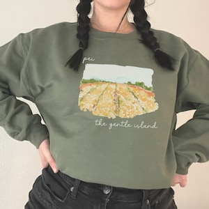 May include: A green sweatshirt with a watercolor illustration of a field with the text "pei the gentle island" printed on the front.