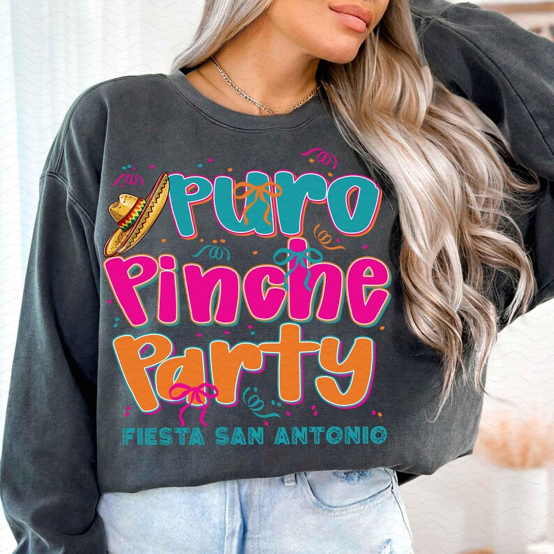 May include: A dark gray sweatshirt with a colorful graphic print that says "Puro Pinche Party" with a sombrero and confetti. The text "Fiesta San Antonio" is printed below the graphic.