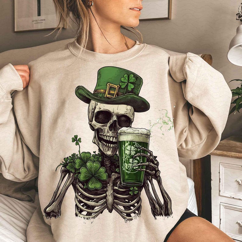 Peut inclure: Sweat-shirt beige avec un motif de squelette portant un chapeau vert orn&eacute; d'un tr&egrave;fle et tenant une bi&egrave;re verte. Des tr&egrave;fles entourent la poitrine du squelette. Th&egrave;me de la Saint-Patrick.