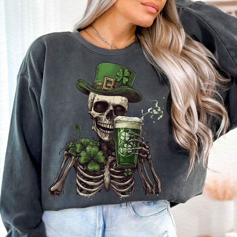 Peut inclure: Sweat-shirt gris fonc&eacute; avec un squelette portant un chapeau vert avec un tr&egrave;fle et tenant une bi&egrave;re verte. Le squelette a un bouquet de tr&egrave;fles et le verre &agrave; bi&egrave;re a un motif de tr&egrave;fle. Le sweat-shirt est sur le th&egrave;me de la Saint-Patrick.