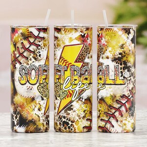 Puede incluir: Tres vasos de acero inoxidable con un dise&ntilde;o amarillo, rojo y negro que presenta una pelota de softball, un rayo y las palabras "Softball Life".