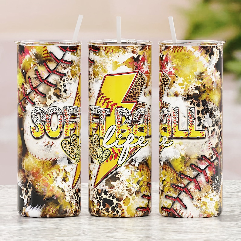 Puede incluir: Tres vasos de acero inoxidable con un dise&ntilde;o amarillo, rojo y negro que presenta una pelota de softball, un rayo y las palabras "Softball Life".
