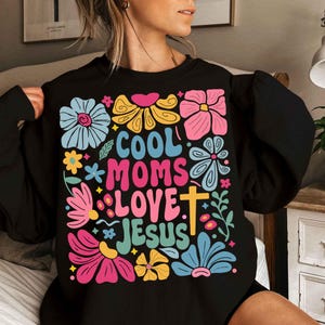 May include: Black sweatshirt with a colorful floral design and the text "Cool Moms Love Jesus".