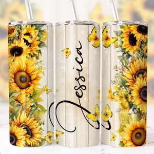 May include: A stainless steel tumbler with a white woodgrain background and a sunflower and butterfly design. The tumbler has the name "Jessica" written on it in a cursive font.