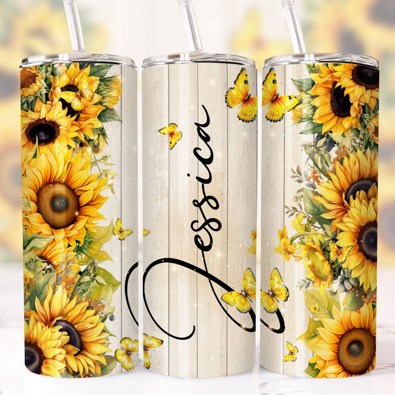 May include: A stainless steel tumbler with a white woodgrain background and a sunflower and butterfly design. The tumbler has the name "Jessica" written on it in a cursive font.